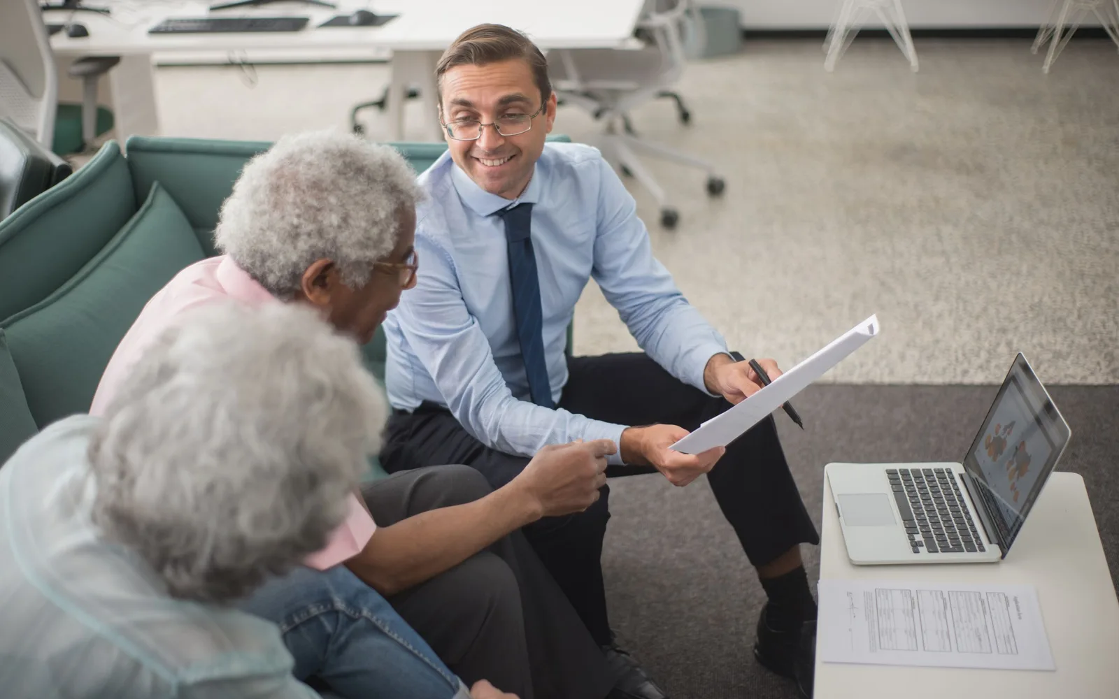 Trois agents du service public souriants discutent avec une conseillère dans une agence lumineuse.